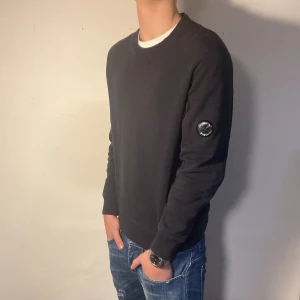 C.P. Company Sweatshirt - Säljer nu denna feta svarta sweatshirt från C.P. Company i väldigt bra skick (Plast skydd på) | Storleken är M men passar även S | Retail ligger på ungefär 2200 | Bara skriv vid minsta lilla fråga eller fundering!