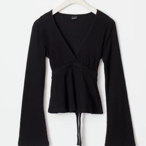 Svart tröja med knyte baktill - Snygg svart omlottopp med långa ärmar och knytband i midjan. Använd få gånger då jag köpte fel storlek. Super bra skick!💕org pris: 299kr