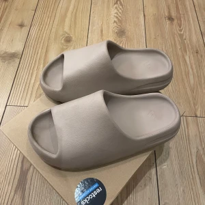 Yeezy slide - Yeezy slides. Är extremt bekväma tofflor men kommer inte till användning längre. Är små i storleken, passar mig som har 38/39. Har lite mörka fläckar men går säkert att få bort. Annars är det inga defekter på dem. Pris kan diskuteras.