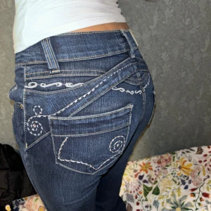 low waist Dolce & Gabbana - Snygga blå jeans från Dolce & Gabbana med unikt vitt broderi på bakfickorna och över höfterna. mått är 36cm i midjan och cirka 80 innerbenslängd