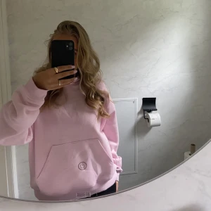 Rosa hoodie - Säljer en mysig rosa hoodie med en stor ficka framtill. Perfekt för en avslappnad stil. Hoodien har långa ärmar och en klassisk huva💗