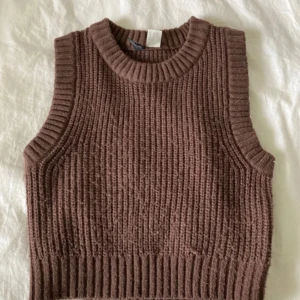 Brun stickad väst - Säljer en mysig brun stickad väst med ribbad design. Perfekt för lager-på-lager under kyligare dagar. Enkel och stilren modell som passar till det mesta.