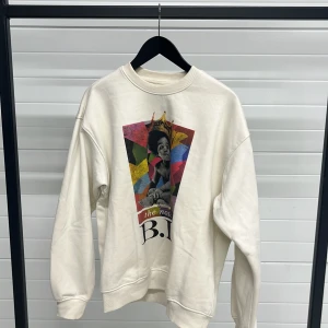 Vit sweatshirt med The Notorious B.I.G. tryck - Säljer en vit sweatshirt från Brooklyn Mint med ett färgglatt tryck av The Notorious B.I.G. på framsidan. Tröjan har långa ärmar och en klassisk rund halsringning. Perfekt för dig som vill ha en stilren men ändå uttrycksfull look. 🎨👑
