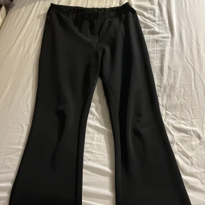 Svarta byxor med slits - Snygga svarta byxor med slits vid bensluten. De har en elegant och stilren design som passar perfekt för olika tillfällen. Byxorna har en rak passform och är tillverkade i ett mjukt material för extra komfort.