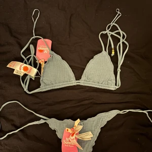 Blå bikini med knytband - Snygg blå bikini från med triangelformad topp och knytband i sidorna. Toppen har justerbara axelband och dekorativa pärlor. Perfekt för en dag på stranden eller vid poolen. Aldrig använd.💗