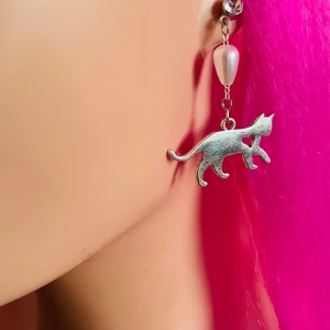 By prisförslag- 1 st Silverfärgat örhängen katt - Charmigt örhängen i silverfärg med ett hängande kattmotiv. Örhänget har en pärldetalj och en liten glittrig sten vid fästet. Perfekta för djurälskare som vill ha något unikt och stilrent.