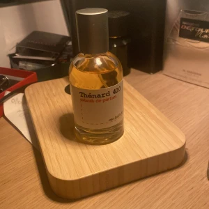 Thénard 400 Eau de Parfum - Säljer en elegant flaska Thénard 400 Eau de Parfum. Flaskan är genomskinlig med en stilren etikett och har en silverfärgad kork. Doften är unik och djärv, perfekt för den som vill sticka ut.