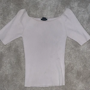 Beige ribbad offshoulder topp från Bik Bok - Säljer en stilren beige ribbad offshoulder topp från Bik Bok. Toppen har korta ärmar och en smickrande passform som passar perfekt för olika tillfällen. Perfekt för dig som vill ha en enkel men elegant look.