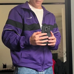 Lila full-zip tröja från Nike - Säljer en otroligt snygg vintage lila full-zip tröja från Nike då den tyvärr är för liten för mig. Tröjan har en oversized passform och är som nyskick. Storlek L.