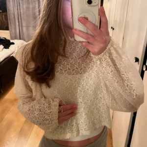 Vit spetsblus - Säljer en elegant vit spetsblus med långa ärmar och volangdetaljer vid axlarna. Perfekt för att lyfta vilken outfit som helst!🌸