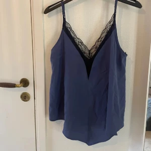Blå linnetopp från Zara - Snygg blå linnetopp från Zara med spetsdetaljer vid halsringningen. Toppen har smala axelband och en avslappnad passform. Perfekt för en stilren look.