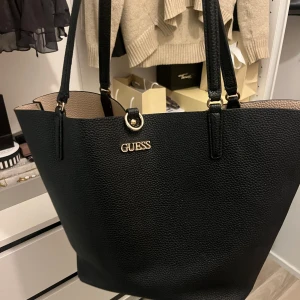 Guess väska  - stor svart guess väska med guld detaljer perfekt för skolan sliten nedtill därav priset köpt för 1099
