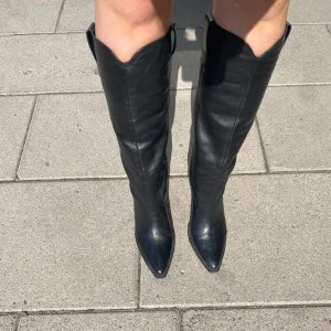 Cowboyboots  - Höga läder cowboyboots i utmärkt skick som endast används några gånger. Skafthöjd: ca  40 cm. Klack: 8 cm  Märket är LeGer by Lena och ord. Pris var 1939 kr. Inköpta december 2023. 