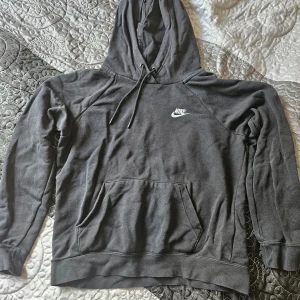 Svart hoodie från Nike - Säljer en snygg och bekväm svart hoodie från Nike. Den har en klassisk design med en känguruficka fram och justerbar huva. Perfekt för både vardag och träning. Den är i bra skick och redo för en ny ägare!