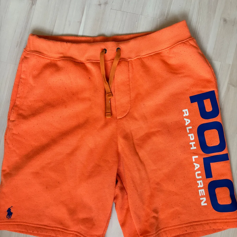 Orangea Ralph lauren shorts med blå text. Dem är lite noppriga (se bild) . Shorts.