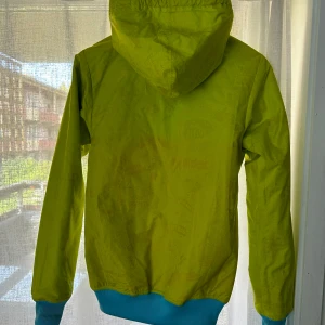 Färgglad vindjacka från Adidas - Säljer en supercool och färgglad vindjacka från Adidas. Jackan har en mix av limegrön, turkos och röd färg som verkligen sticker ut. Den har en dragkedja framtill och en huva med färgglada snören. Finns i XS och L