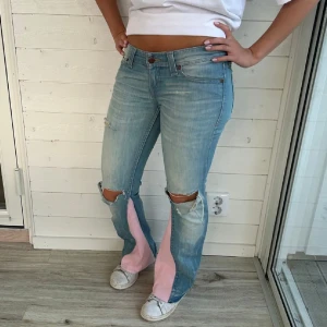 Ljusblåa jeans med hål - Ljusblåa jeans med rosa detaljer. Strl xs midjemått 37x2 cm innerbenslängd 78cm. Bilder från Jeans Arkivet💕