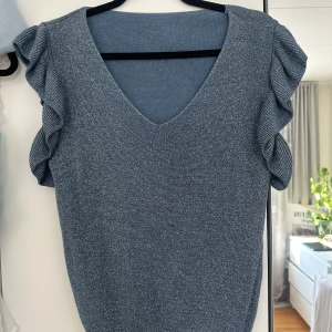 Glittrig blus - Jättesöt blåglittrig blus/topp med volangärm. Köpt för flera år sen i en liten butik så vet tyvärr ej märke