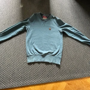 Blå fleece tröja från Parajumpers - Säljer en snygg blå fleece tröja från Parajumpers i storlek XS. Tröjan har en enkel design med ett litet märke på bröstet och är perfekt för kyliga dagar. Den är långärmad och supermjuk, vilket gör den både bekväm och stilren. Perfekt för höst och vinter!
