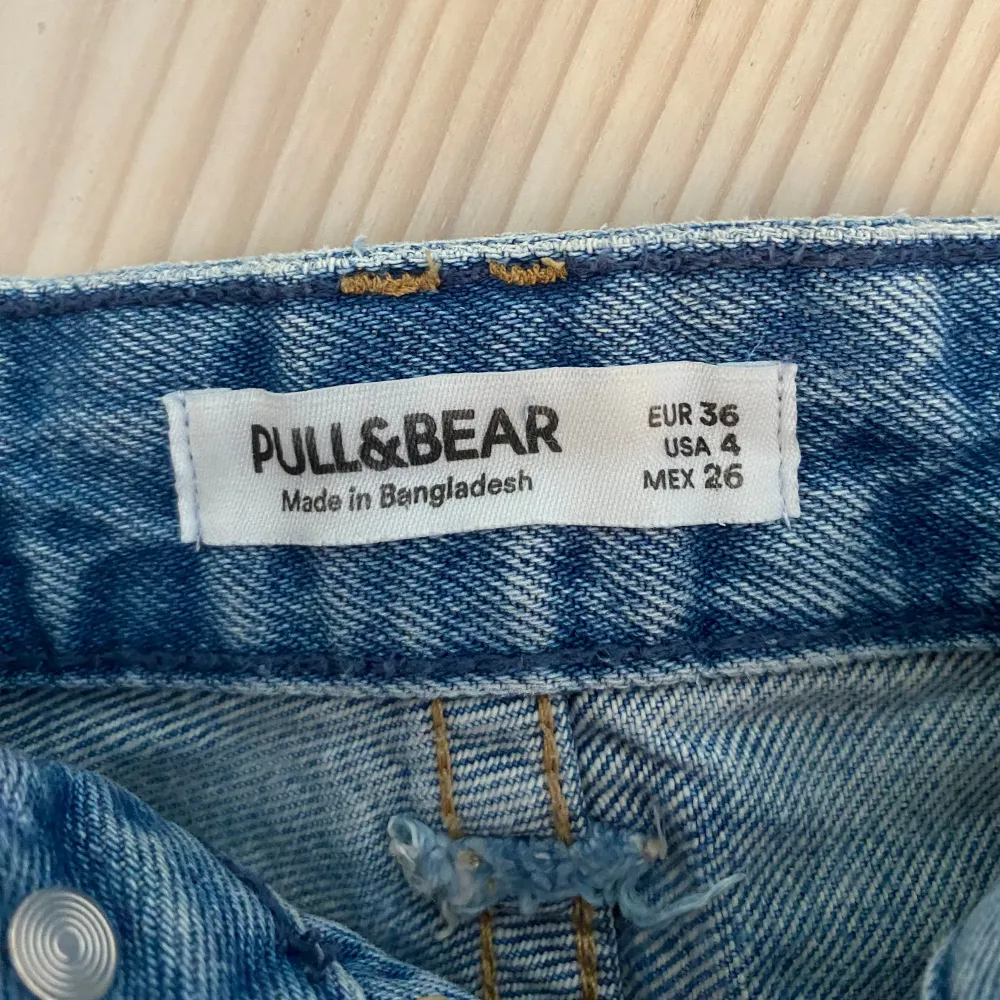 Säljer ett par snygga blå low waist jeansshorts från Pull&Bear i storlek 36. De har en cool, sliten look med fransiga kanter och slitningar på fram- och baksidan. Perfekta för sommaren och festivaler. Använda typ 2 gånger❤️. Shorts.