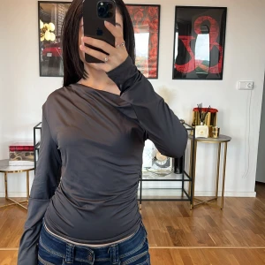 Mörkgrå långärmad topp - Säljer en snygg mörkgrå långärmad topp i ett mjukt och stretchigt material. Perfekt för både vardag och fest! Toppen har en åtsittande passform som framhäver figuren och är superbekväm att bära. Passar perfekt till jeans eller kjol för en stilren look.