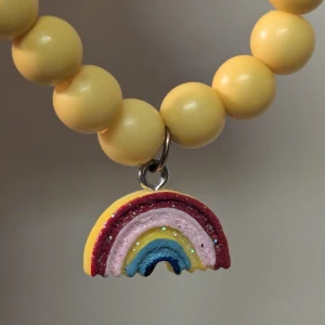 Gult barn pärlarmband med regnbågshänge - Superfint gult pärlarmband med ett färgglatt regnbågshänge. Perfekt för att liva upp vilken outfit som helst! 