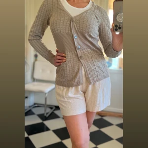 b.young beige kofta, storlek M - Snygg stickad kofta i beige färg med knappar framtill. Den har två fickor på framsidan och en v-ringning. Nyskick.