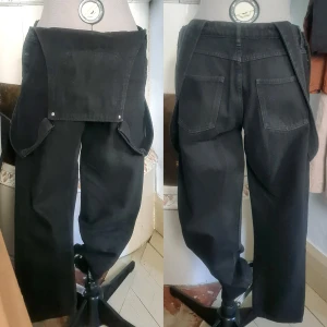 Monki hängselbyxor denim/jeans svarta S - För korta för mig, fint skick. Lite överexponerade bilder för att visa detaljer, de är mörkt svarta. 100% bomull Mått  cm: Midja vidd: 41 Stuss vidd: 53 Gren till överkant fram: 50 Benöppning vidd: 17 Innerbenslängd: 64 Hängslen längd: upp till 70