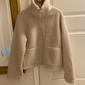 NY naturvit pilejacka / teddyjacka HM - Ny med tags  H&M. Färg: ljusbeige. Storlek: L. Ta en storlek större än din vanliga storlek om du vill ha plats för en tjocktröja under annars kan det blir lite tajt. Dvs har du normalt S eller M i vanliga fall så blir denna en lagom oversizejacka. 