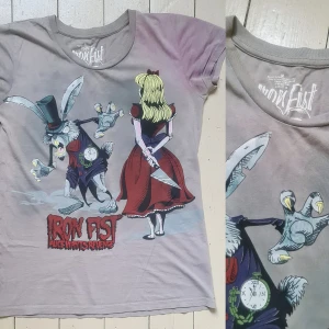 T-shirt med tryck grå M iron fist - Fint skick, flammigheten är som den ska vara. 100% bomull. Vidd: 47-49, längd: 67.