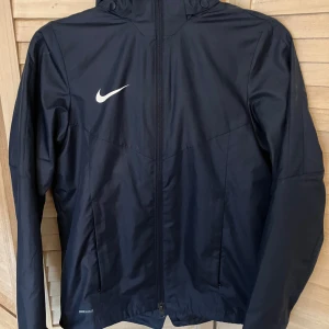Nike vind/ regnjacka.  - Fin regn/ vindjacka. Tunt fleece foder i halslinning, meshfoder övrigt. Fint skick, inget synligt slitage. 