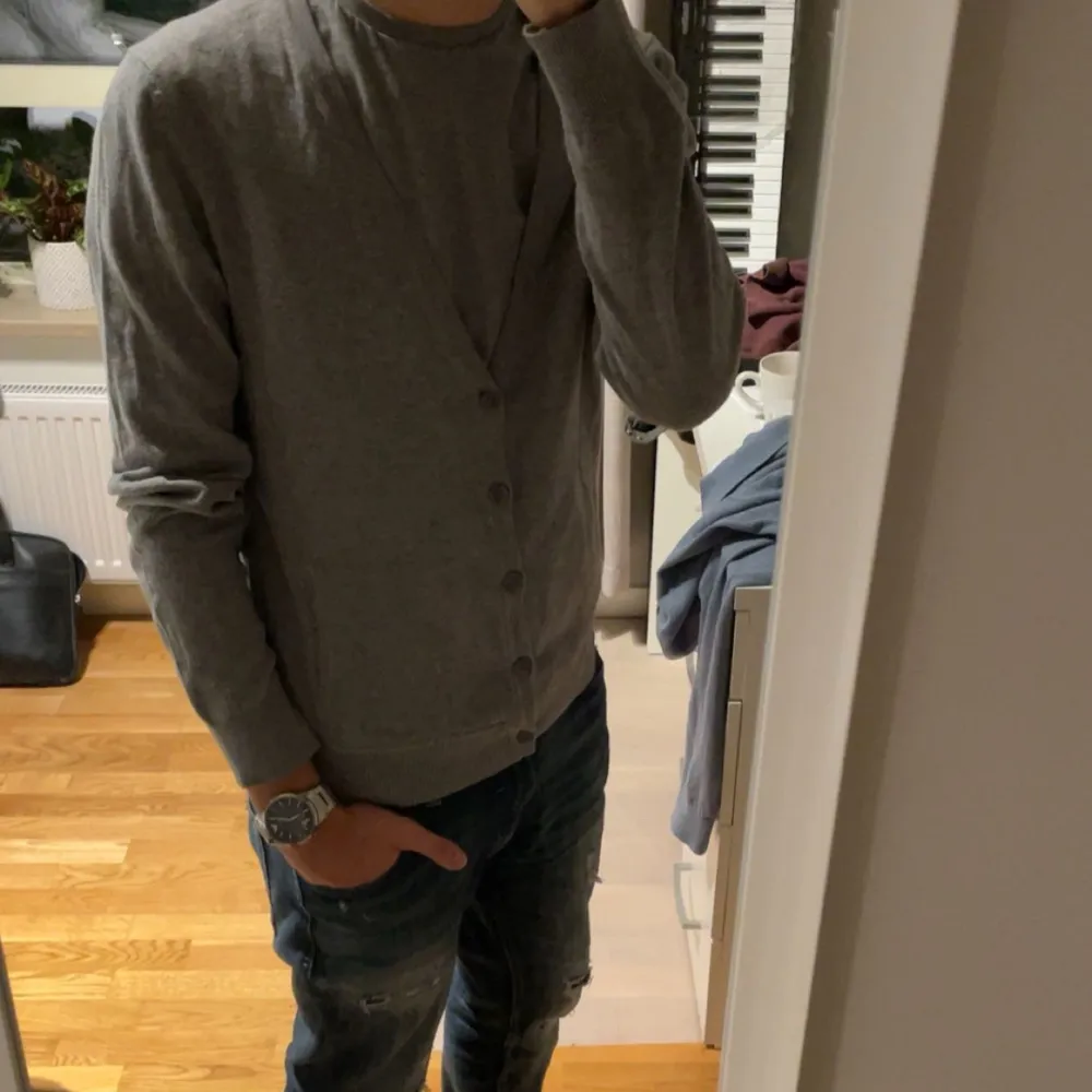 Säljer en stilren grå kofta i normal passform. Perfekt för både vardag och lite finare tillfällen. Den har långa ärmar och knappar framtill. Passar bra till jeans eller chinos för en avslappnad look.. Tröjor & Koftor.