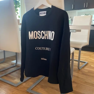 Svart tröja från Moschino - Säljer en snygg svart tröja från Moschino. Den har en klassisk design med vit text på framsidan. Köpt på nk för cirka 3 år sedan för 3000 kr. Tröjan är i bra skick och redo för en ny ägare men mitt namn står på en lapp i tröjan skriv till mig om ni har frågor! 