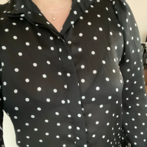 Tunn svart blus - Jättefin blus i tunt material med vita prickar och knäppe som en skjorta.