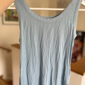 Ljusblå ribbad linnetopp - Säljer en ljusblå ribbad linnetopp i ett mjukt och stretchigt material. Perfekt för sommardagar eller som ett lager under en kofta. Toppen är ärmlös och har en enkel, stilren design. Passar till både jeans och kjol!