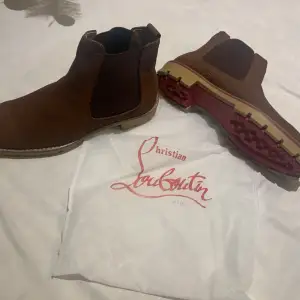 Säljer ett par snygga bruna Chelsea boots från Christian Louboutin. De har den klassiska röda sulan och är i skinn. Perfekta för höst, vinter och våren med en stilren design och bekväm passform. Använd dem för en elegant touch till din outfit!