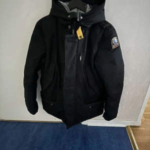 Svart vinterjacka med huva Parajumper - Säljer en svart vinterjacka från Parajumpers i mycket bra skick. Jackan har en praktisk huva och stängs med både dragkedja och knappar. Perfekt för kalla vinterdagar! 🖤vid snabb köp kan vi diskutera priset 