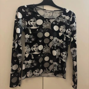 Mönstrad långärmad topp - Säljer en unik långärmad topp med ett svartvitt mönster av kvinnliga ansikten, blommor och cirklar. Materialet är mjukt och stretchigt, mycket bra skick