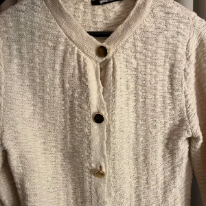 Beige vit kofta med guldknappar - Säljer en beige vit stickad kofta med guldknappar från Gina Tricot. Den har en liten fläck fram men den syns knappt och inget man tänker på, annars bra skick. Pris kan diskuteras🩷