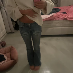 Blå bootcut jeans - Säljer ett par snygga blå bootcut jeans i bra skick. De är lågmidjade och har snygga broderade detaljer på bakfickorna. Perfekta för både vardag och fest! Passar bra till en avslappnad stil eller med klackar för en mer uppklädd look. Tyvärr hål mellan bena men inget som syns när du står, sitter eller går 