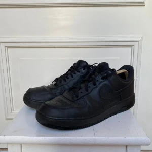 Svarta Nike Air Force sneakers - Säljer ett par klassiska svarta Nike Air Force sneakers i skinn. De är i bra skick med snörning och en stilren design som passar till allt. Perfekta för både vardag och fest. Storlek herr 45.