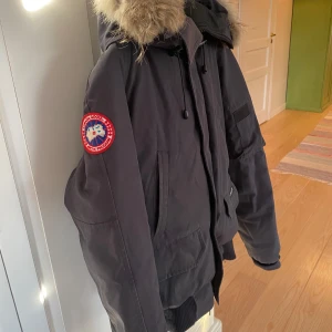  parkajacka från Canada Goose - Säljer en svart parkajacka från Canada Goose i mycket bra skick. Jackan har en avtagbar huva med äkta päls och flera praktiska fickor. Perfekt för kalla vinterdagar! 