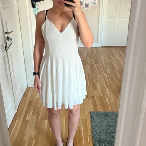 Vit klänning från BikBok - Säljer en superfin vit klänning från BikBok i storlek S. Den har en v-ringad design och smala axelband med snygg snörning i ryggen. Perfekt för skolavslutning eller student. Materialet känns mjukt och skönt mot huden. Passar perfekt för en stilren look! 🌟 Axelbanden är icke justerbara men jag har sytt upp dem lite men det går lätt att sprätta upp om man vill ha banden längre 💕