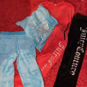 Juicy Couture mjukisbyxor i olika färger - Säljer tre par Juicy Couture mjukis sätt i blått, rött och svart. De är gjorda av mjuk sammet och har glittriga detaljer med texten 'Juicy Couture' längs benen. Perfekta för en avslappnad och stilren look. Alla byxorna har en loose passform och är i mycket bra skick. Inga hål. Helt oanvända och nya. Köpta för 450kr per sätt. Detta är 3 sätt och jag säljer ALLT för 600kr!. Storleken passar även för dem som har S!