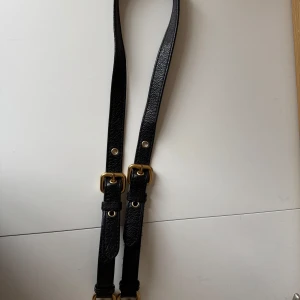 Svart axelrem från Marc by Marc Jacobs - Svart axelrem, oundvikligt skav på klämmorna där väskan suttit fast. Mått på enbart remmen så som fästena sitter är ca 89 cm 