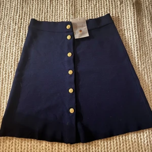 Helt Ny: kjol från Busnel stl 36 - Säljer en oanvänd kjol från Busnel i storlek 36. Kjolen har snygga guldknappar med 'B' logotypen framtill och är i ett klassiskt snitt. Helt ny med lappar. 