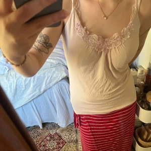 Ljusrosa linne😊💗 - Säljer ett fint rosa linne med vackra spetsdetaljer och blommönster vid halsringningen. Linnet har smala axelband och en mjuk, bekväm passform. 