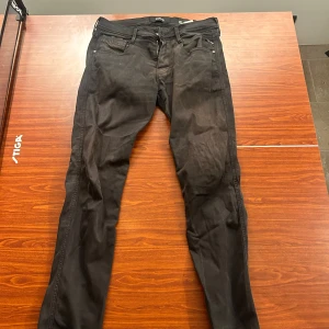 Replay anbass  - Snygga svarta Replay Anbass jeans med dragkedja och knappstängning. Klassisk femficksdesign och diskret Replay-logga på bakfickan. Perfekta för en stilren look. Storlek 29/32