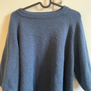 Blå stickad tröja - Mysig blå stickad tröja med rund halsringning och långa ärmar. Perfekt för kyligare dagar och ger en avslappnad stil. Passar bra till jeans eller kjol.