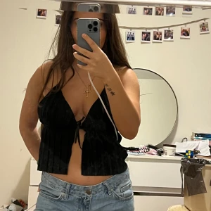 Svart knyt topp - Snygg svart topp med knytning fram och smala axelband. Toppen har en luftig passform och är perfekt för varma dagar. Passar från xs till M. Aldrig använd 